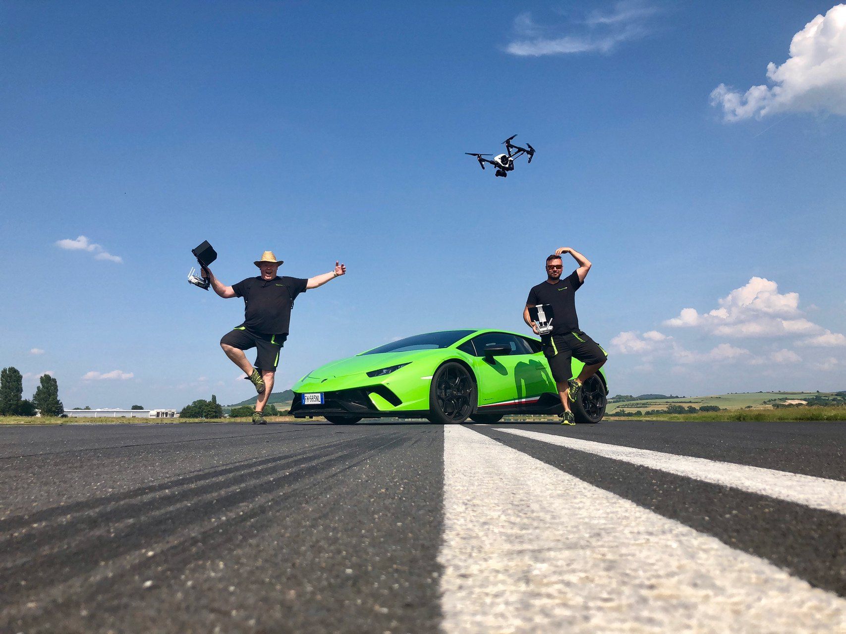 Filmdrohne schwebt über Lamborghini, Nils und Robert stehen auf einem Bein