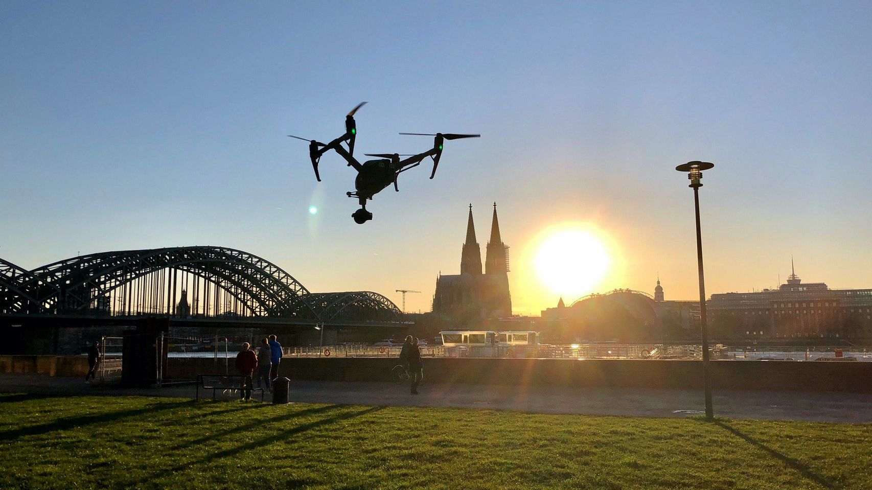 Filmdrohne fliegt im Sonnenuntergang auf Kölner Dom zu und macht Luftaufnahmen